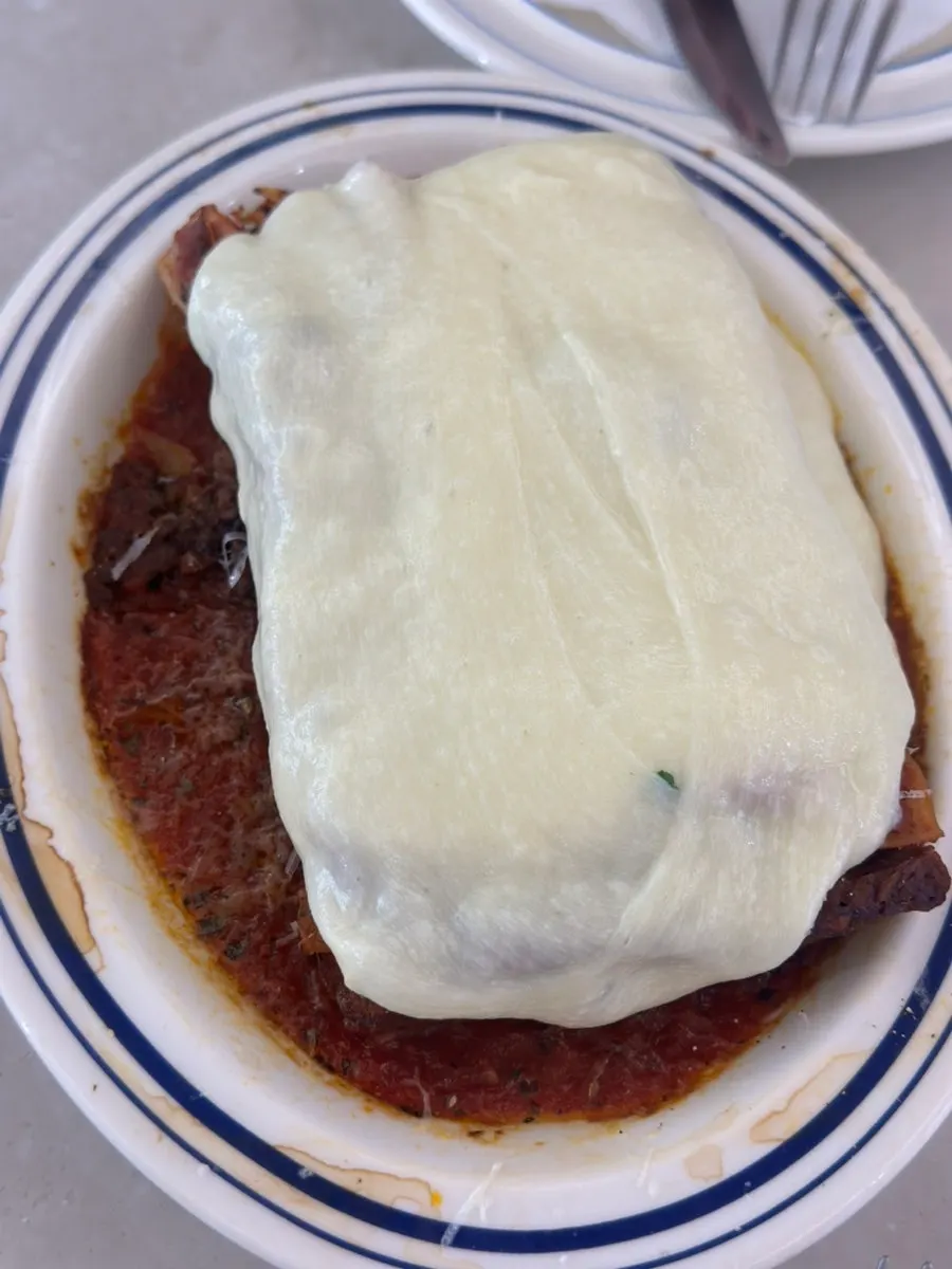 Cheese being poured over the Seongsu lasagna as it's served
