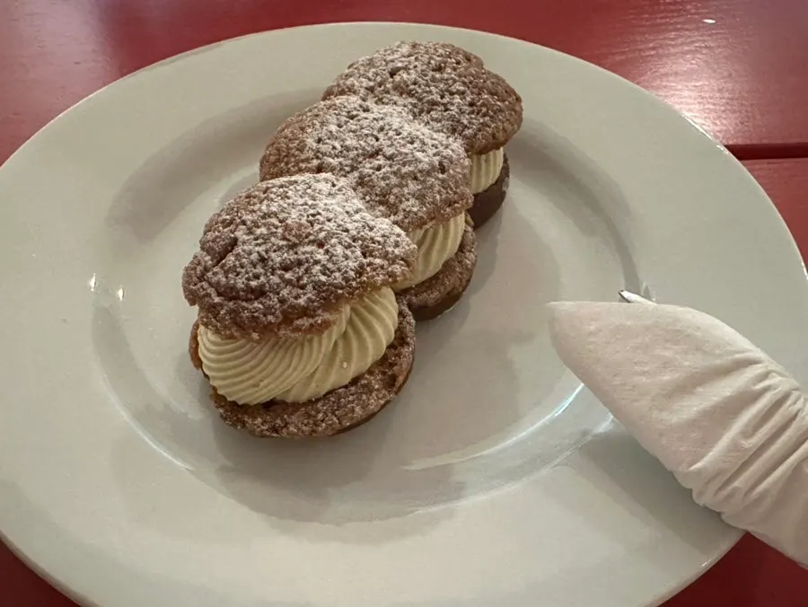 A pistachio cream puff piled generously with cream