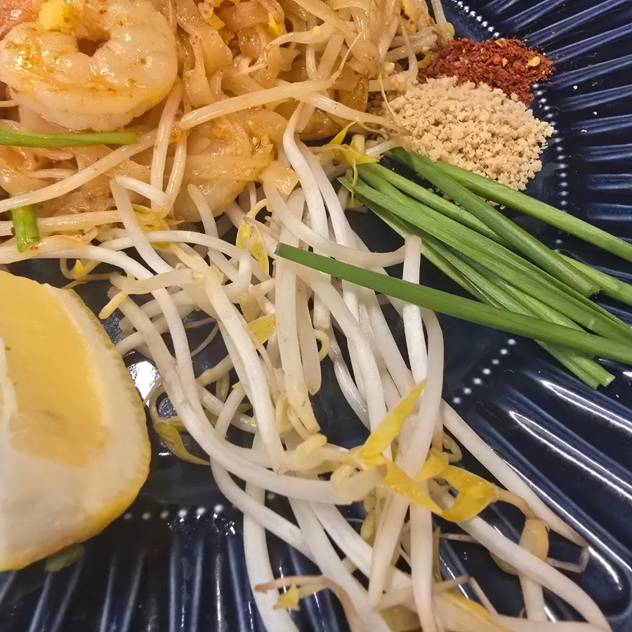 A bite of pad thai with bean sprouts and chives