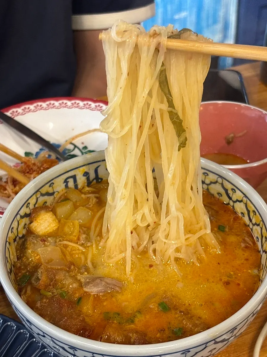 Lifting noodles from the curry tripe pho