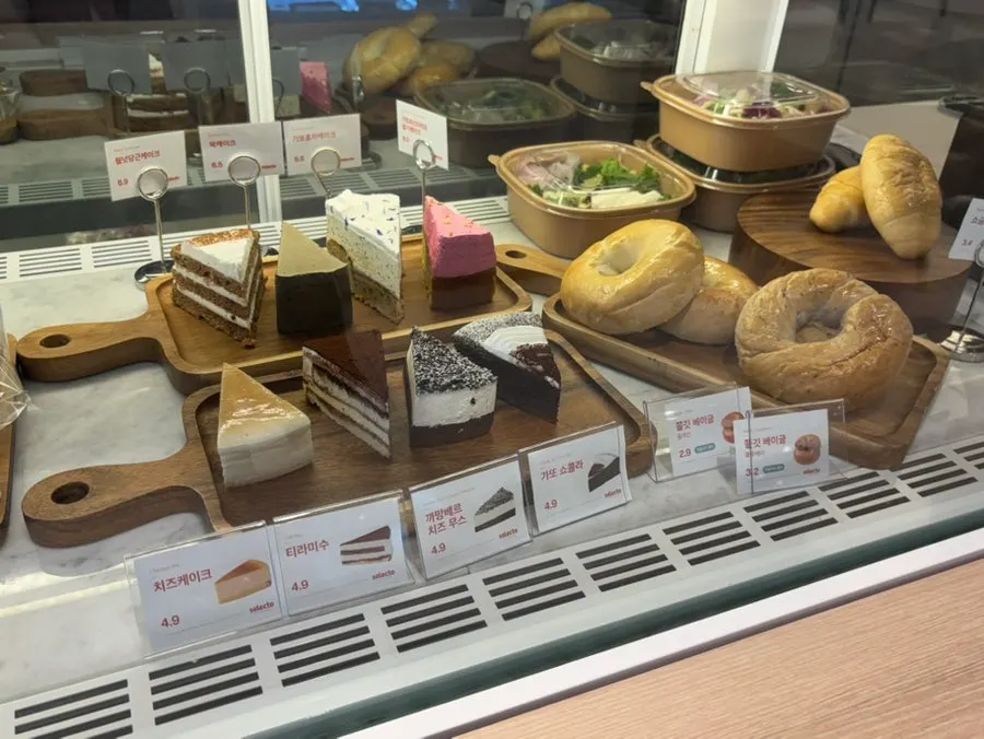 Display case with slice cakes, bagels, and salad