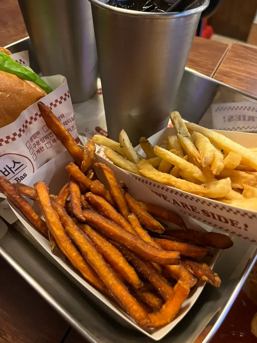 Two burger sets on the table with French fries and sweet potato fries
