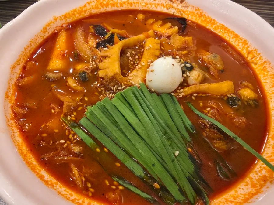 A bowl of jjamppong with seafood and a quail egg