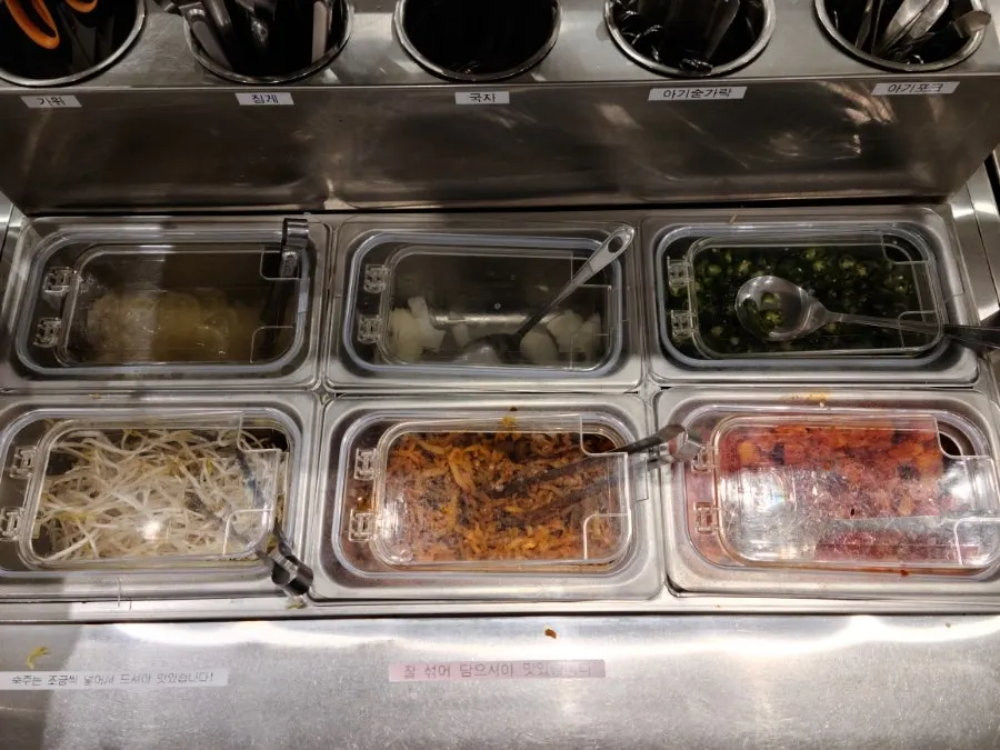Containers of raw onion and mung bean sprouts at the self-bar