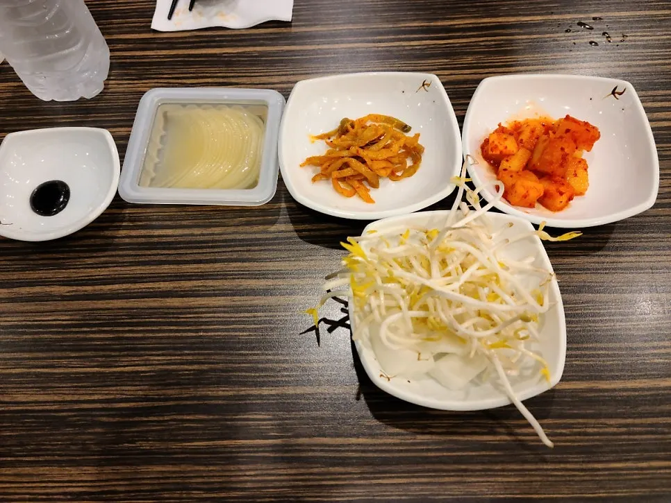 Table set with disposable water cup, bottled water, and side dishes