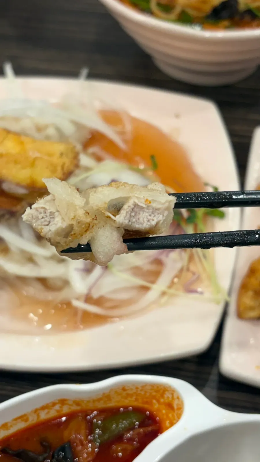A piece of crispy rice pork dipped in sauce
