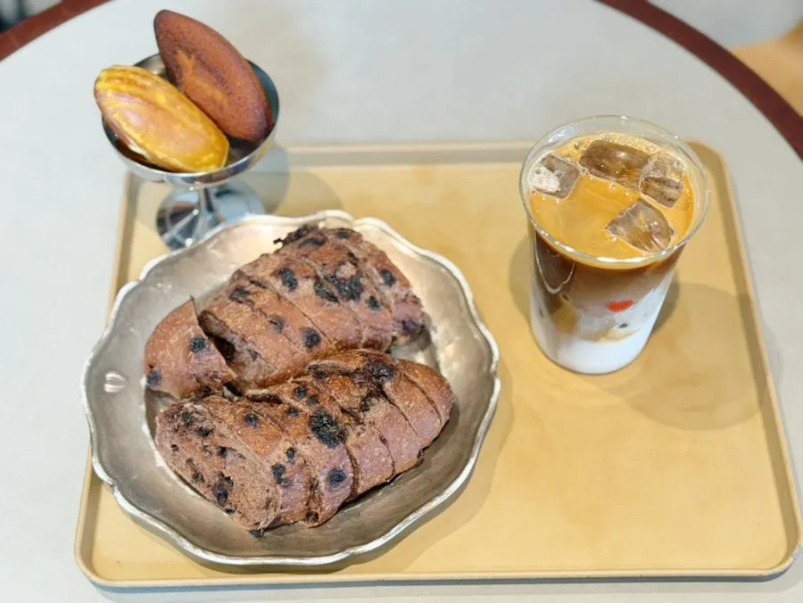 Iced café latte, chocolate baguette, and madeleines set on the table
