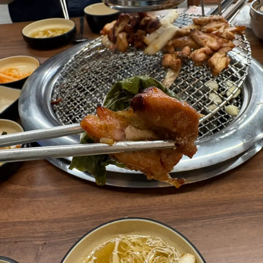 A piece of dakgalbi placed on perilla leaf sauce