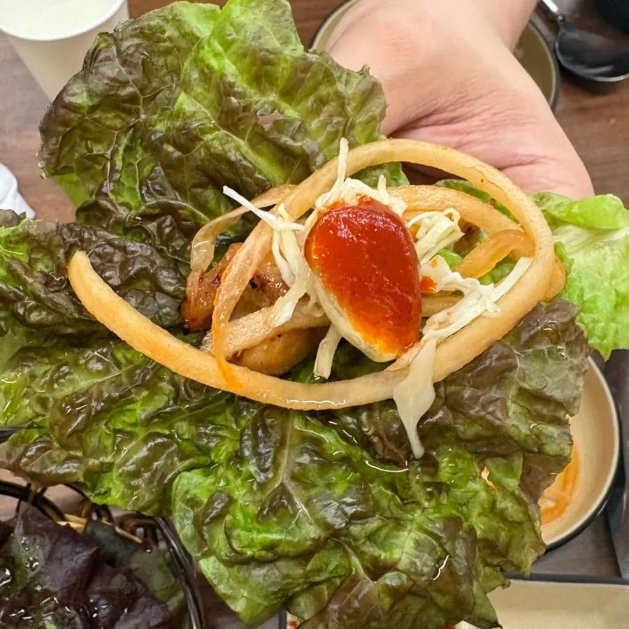 A wrap piled with dakgalbi and side dishes