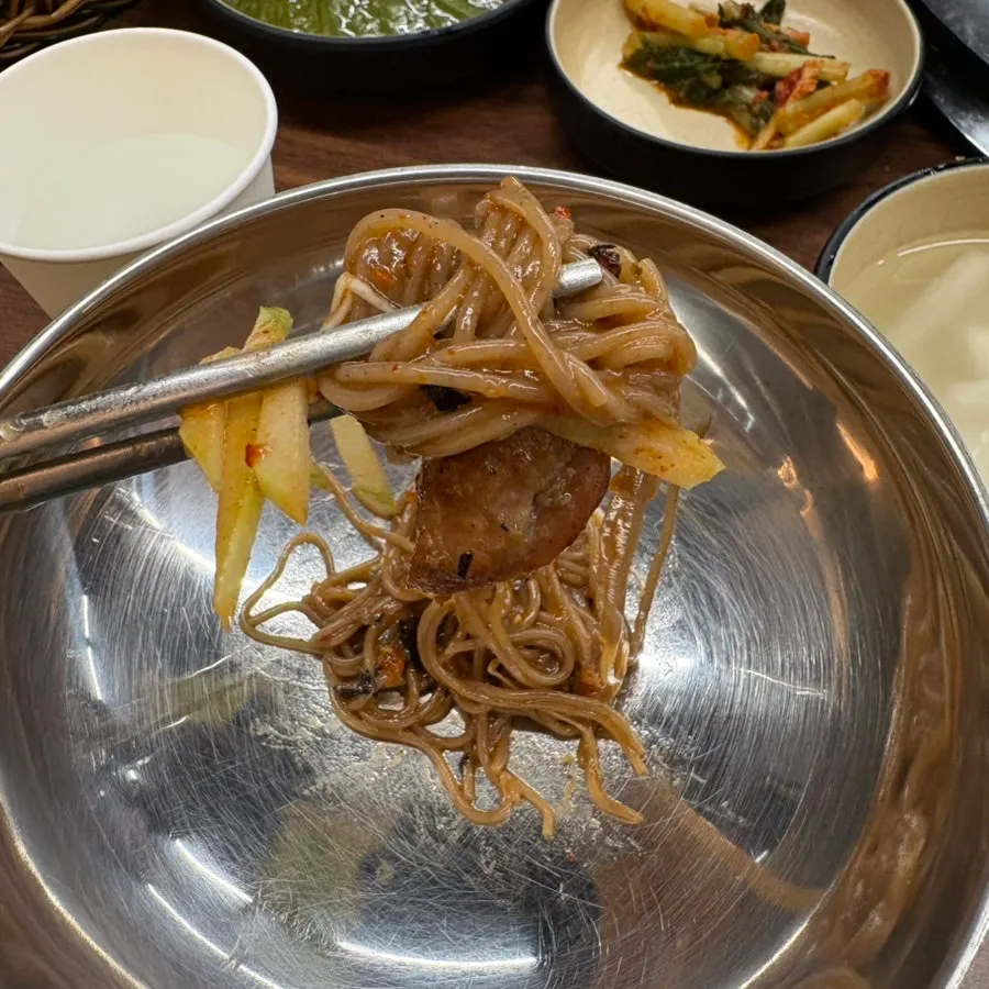 A piece of dakgalbi placed on top of the makguksu
