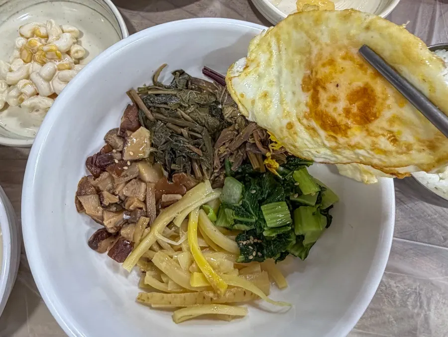Wild greens bibimbap topped with fried egg, served with sundubu