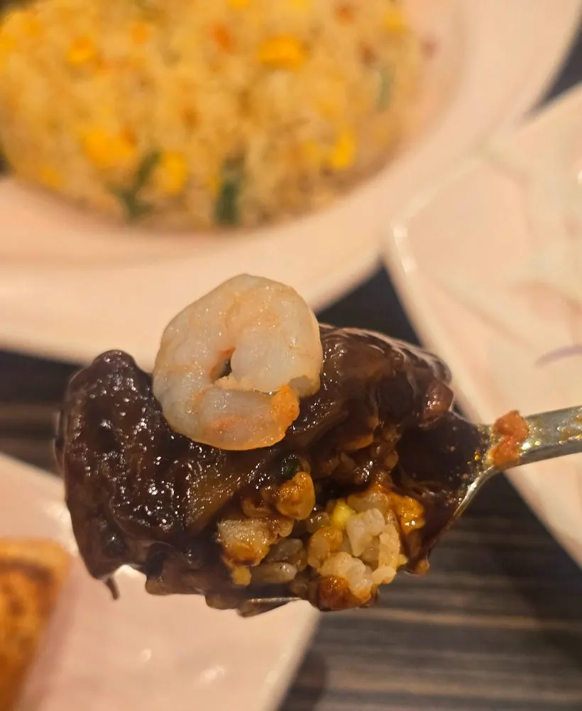 A bite of shrimp fried rice topped with jjajang sauce
