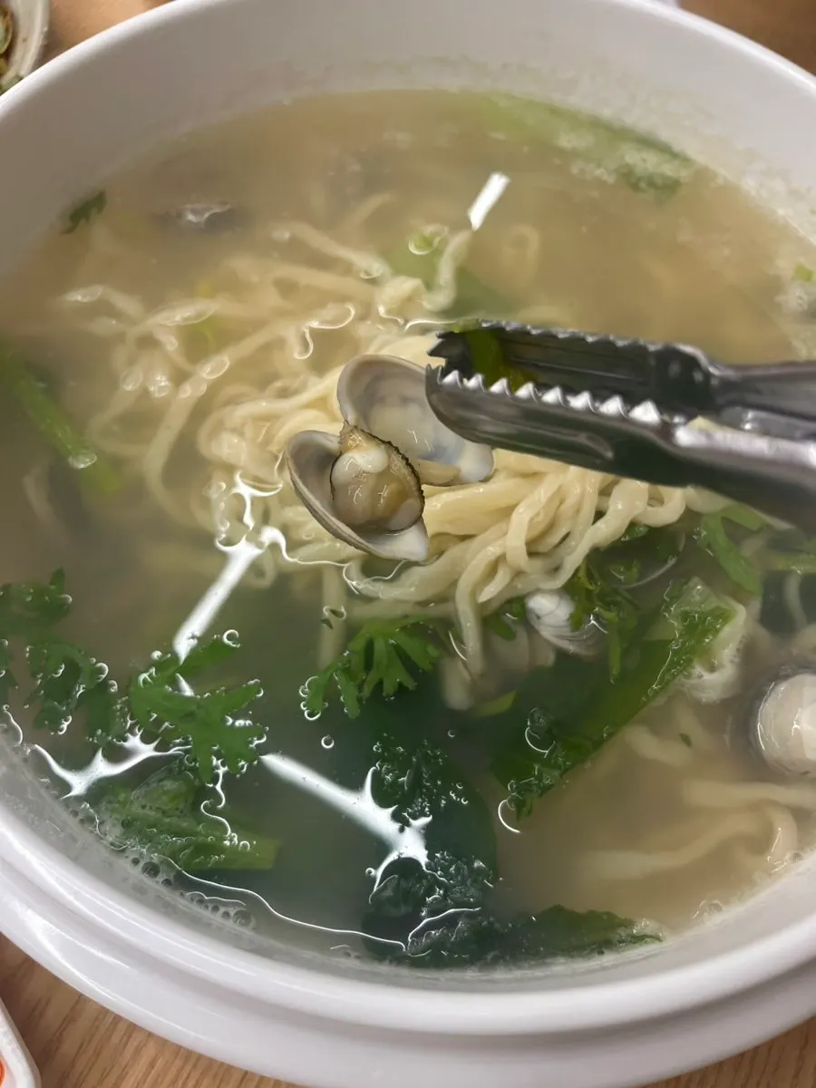 Clam kalguksu noodles lifted with chopsticks
