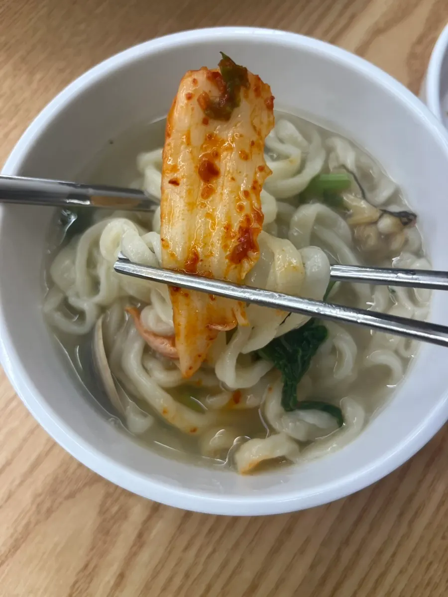 Kalguksu topped with a piece of kimchi