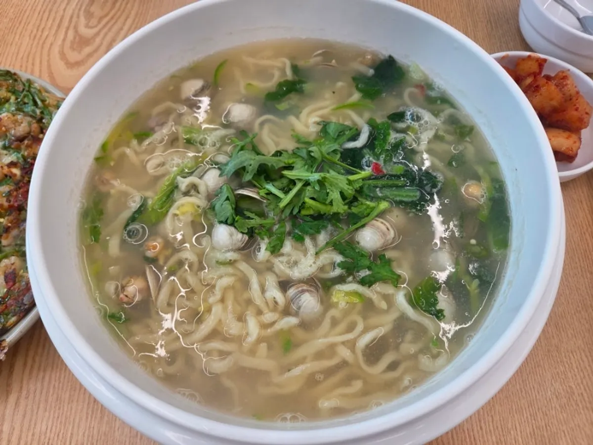 Large bowls of dongjuk kalguksu and seafood pancake served together