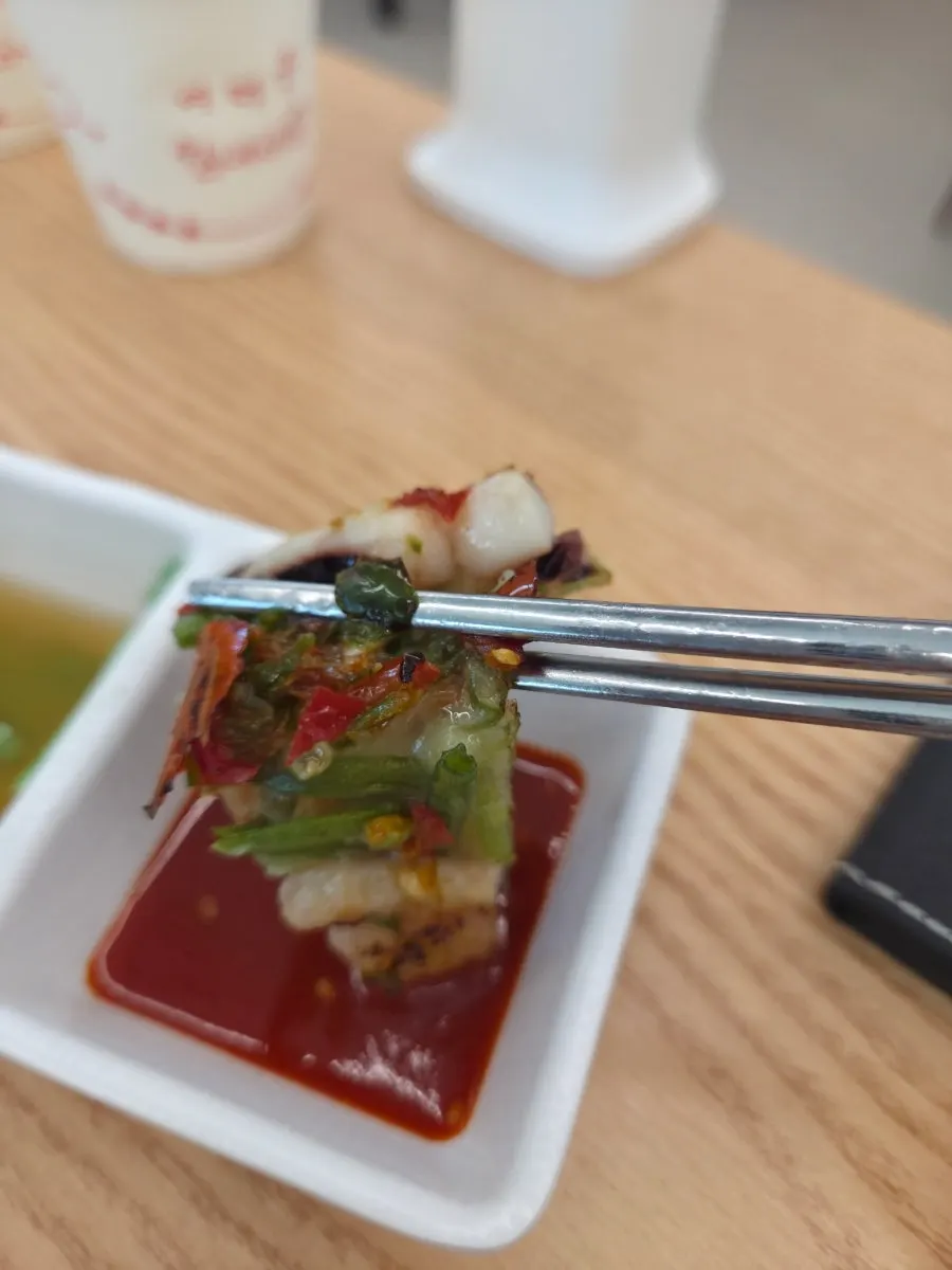 A piece of seafood pancake dipped in sauce