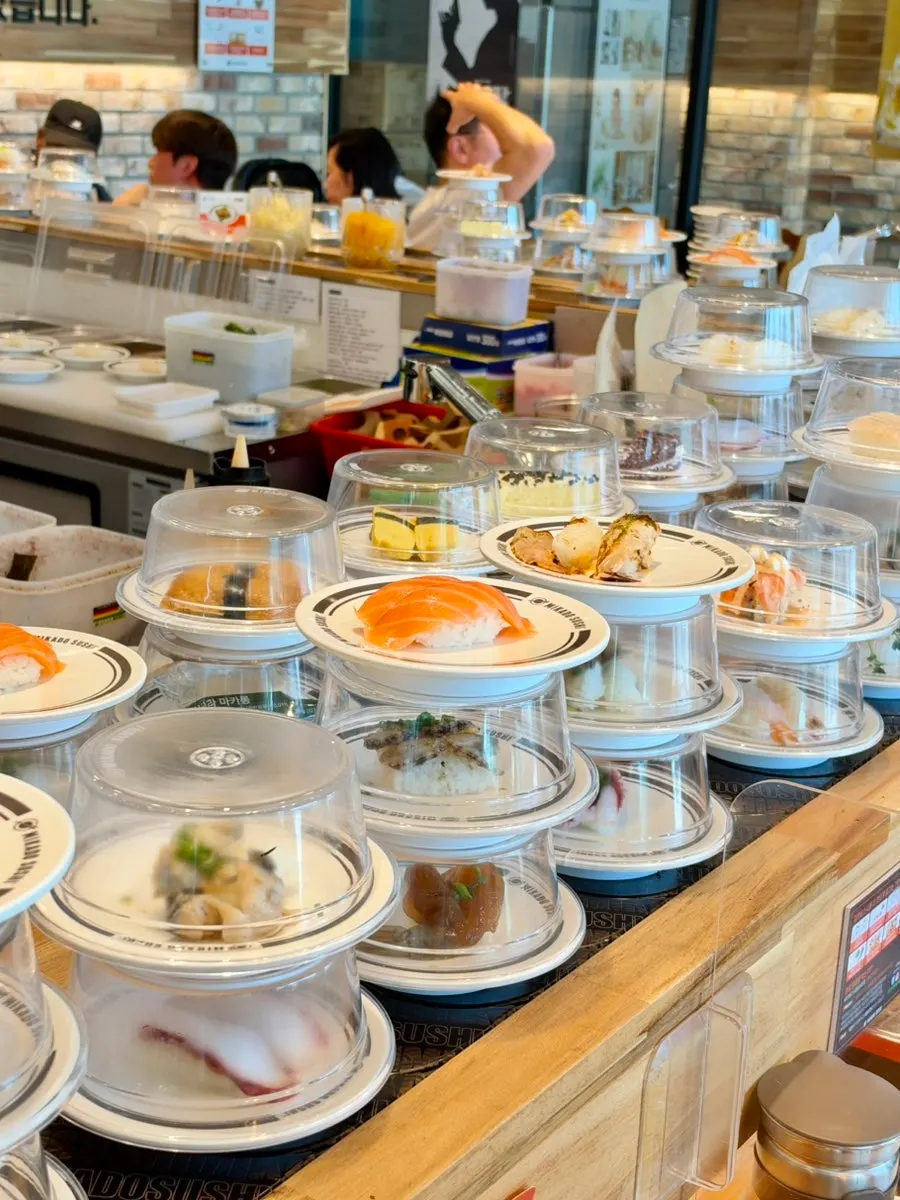 Sushi stacked two to three tiers high on the conveyor belt