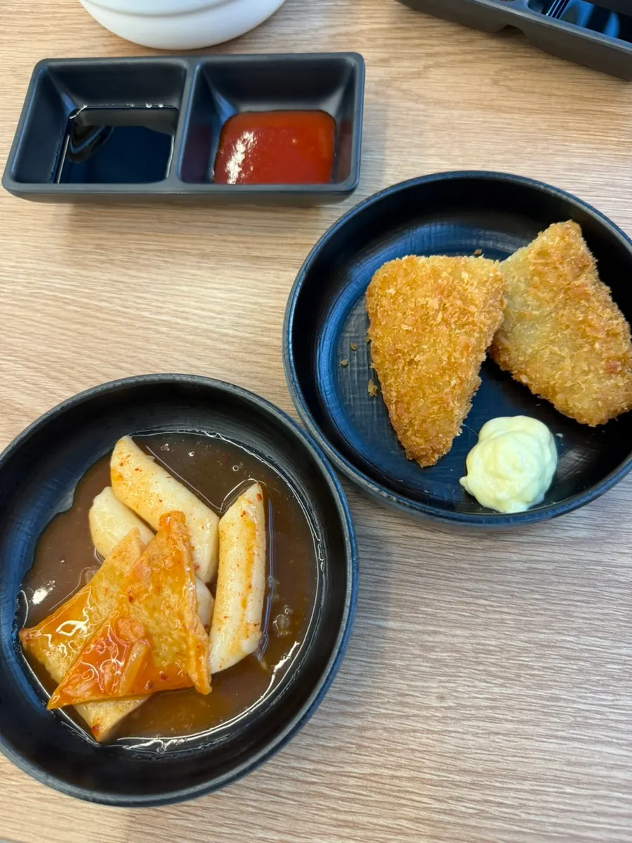 A plate of tteokbokki and fried fish cutlets from the self-serve bar
