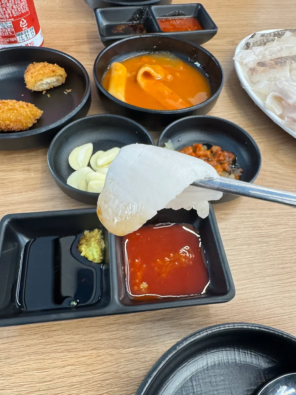 A piece of sashimi picked up with chopsticks