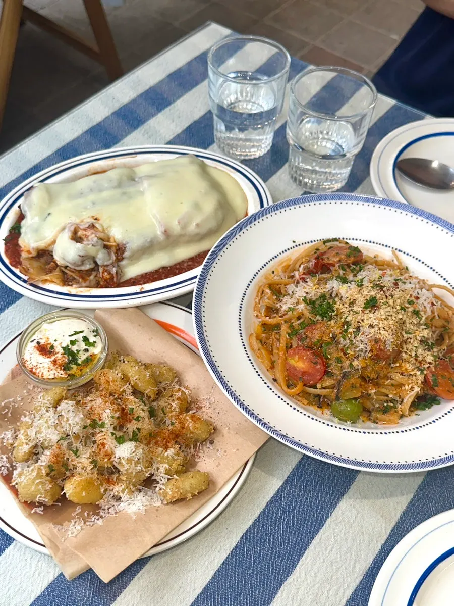 Table setting with aligot cheese lasagna and puttanesca pasta