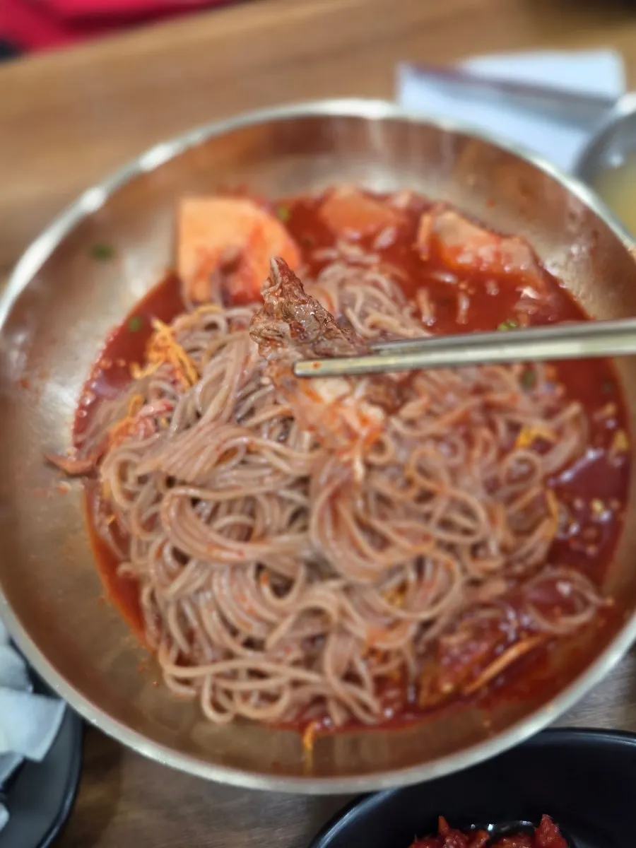 Bibim naengmyeon noodles lifted with chopsticks