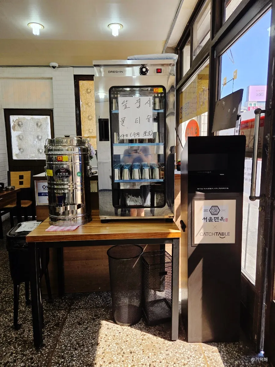 Self-serve warm broth, cups, and small plates by the entrance
