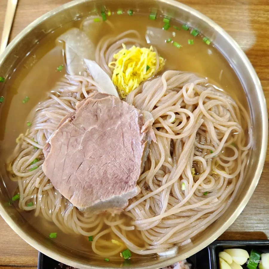 Lifting up a bite of pyongyang naengmyeon noodles