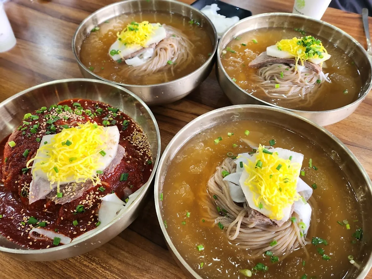 A full spread of Seoul Myeonok's pyongyang naengmyeon, bibim naengmyeon, and hand-dumplings