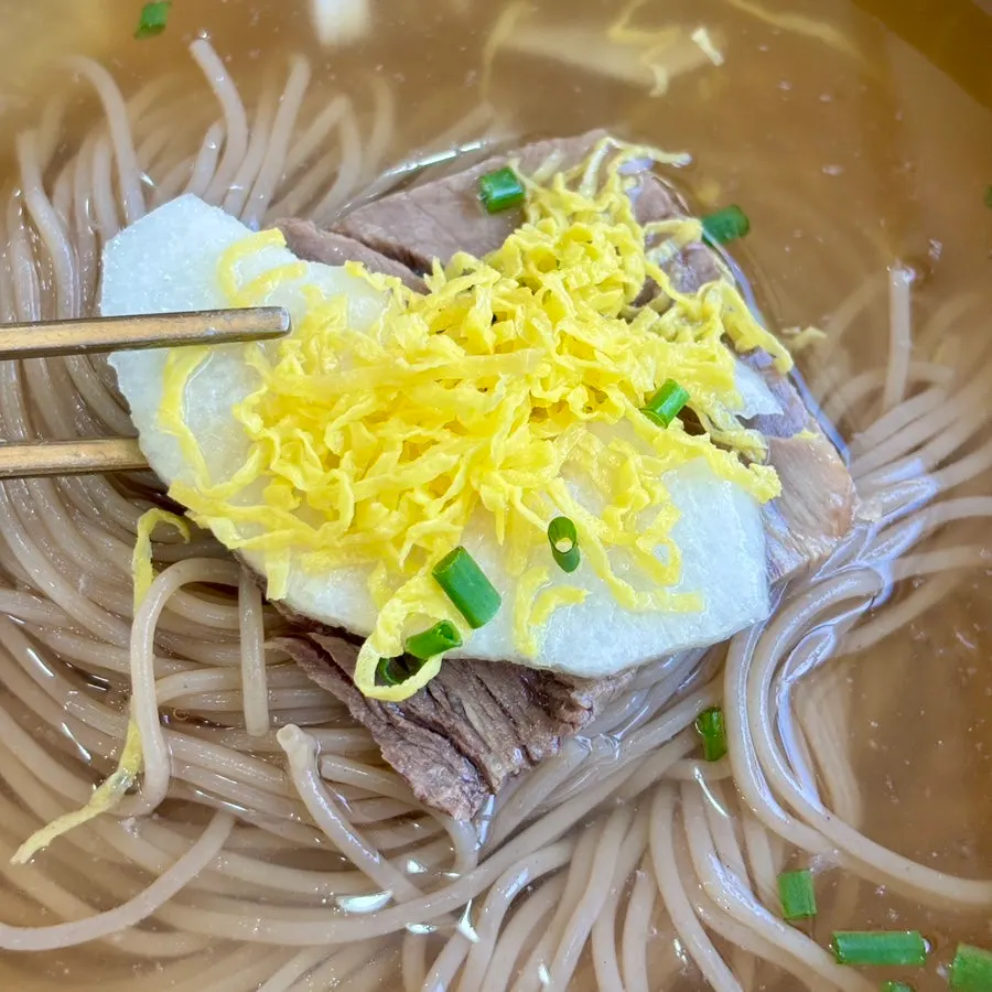A slice each of meat and pear as toppings on the naengmyeon