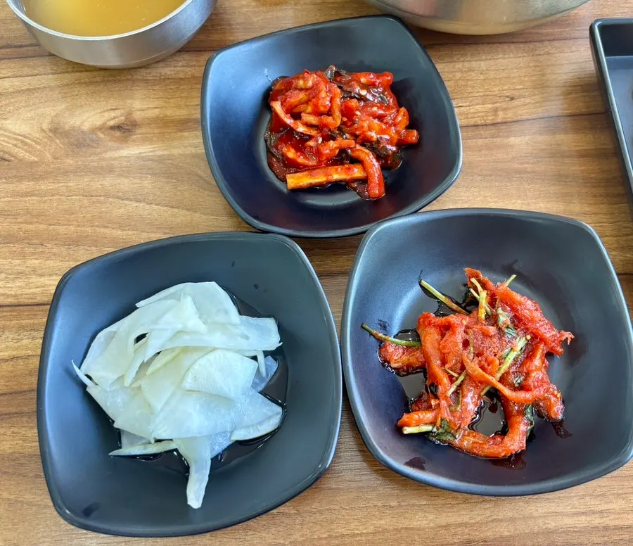 Naengmyeon kimchi, pickled radish strips, and seasoned pollack side dishes