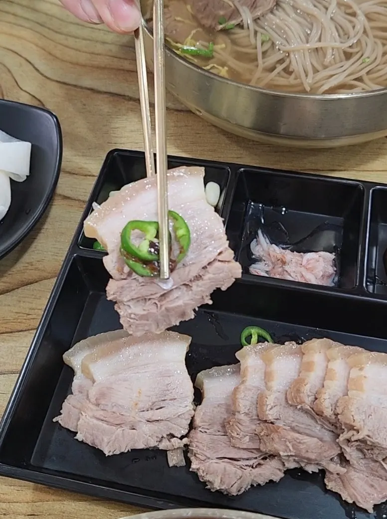 수육 한 점을 집어 든 모습