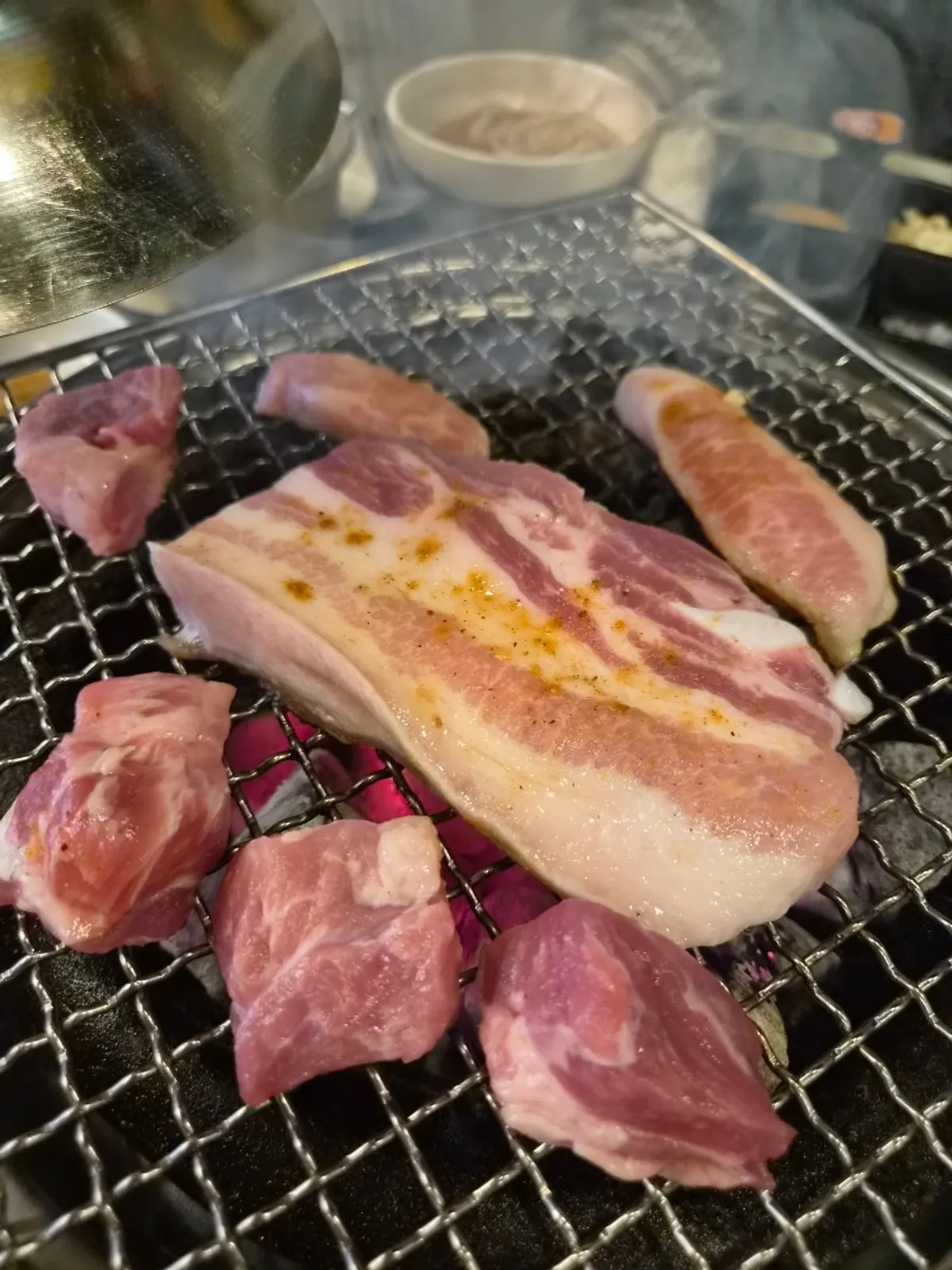 Pork belly grilling over charcoal