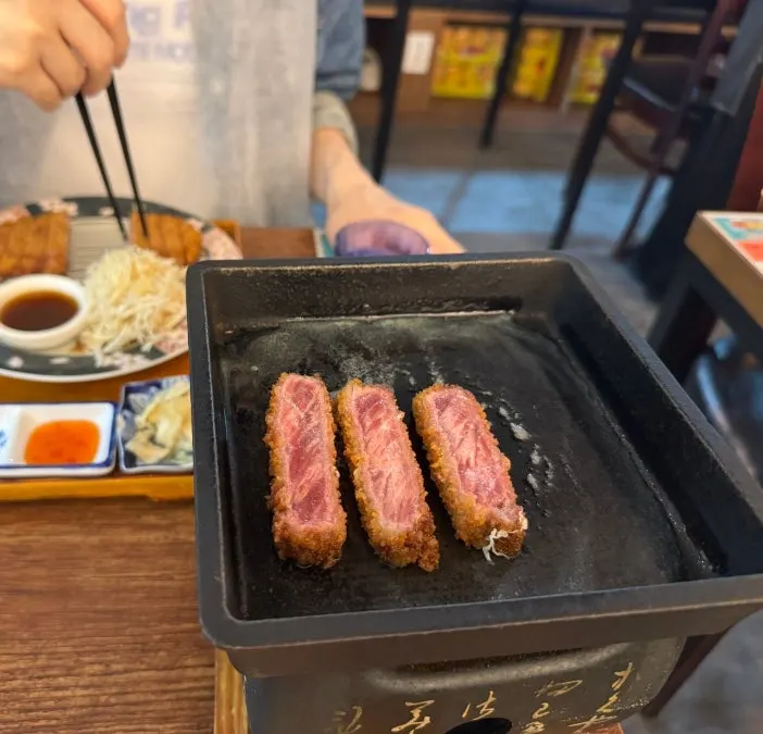 Butter and gyukatsu cooking on a tabletop grill