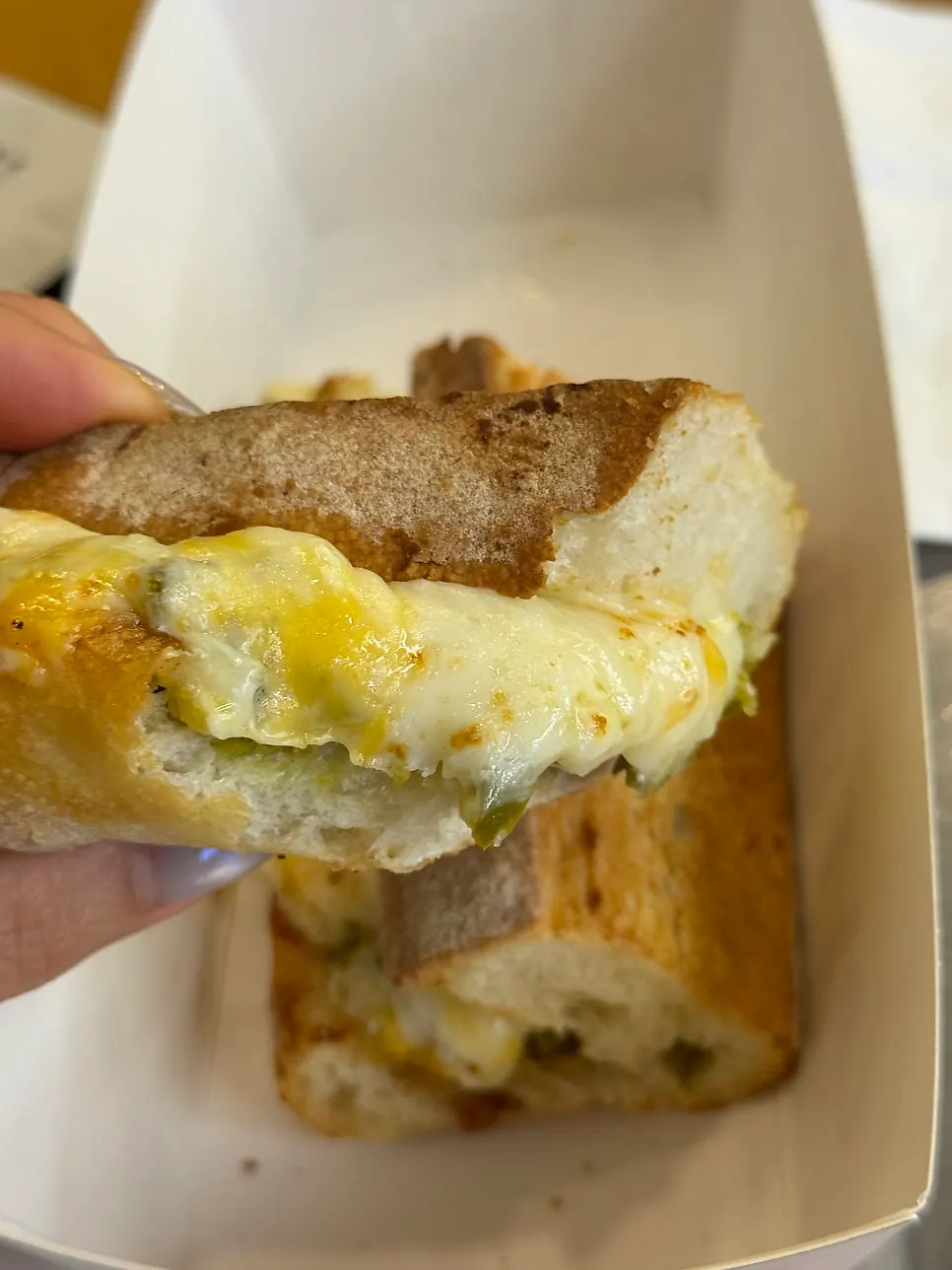 A bite of the grilled cheese sandwich showing jalapeño