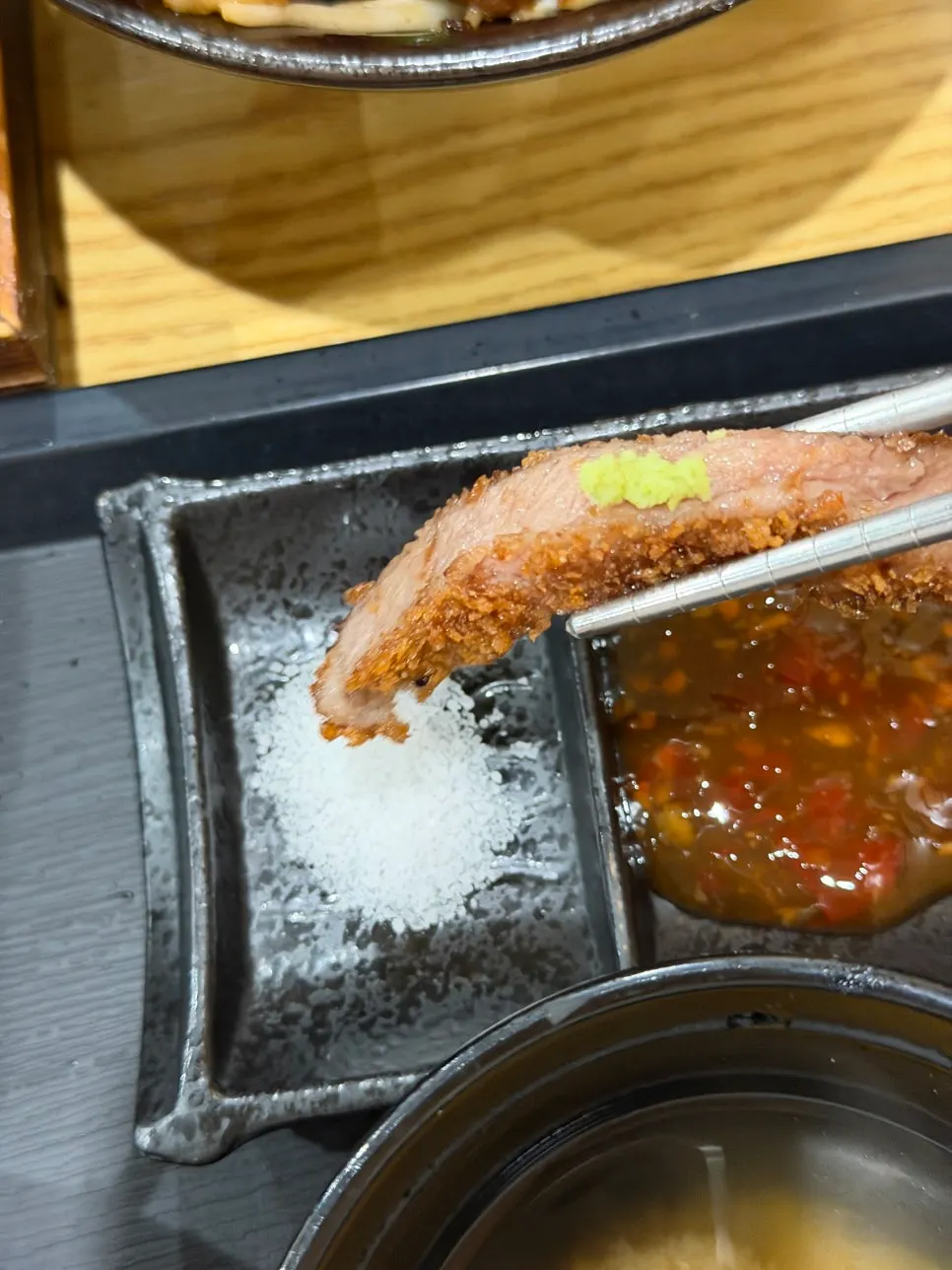 A piece of gyukatsu topped with wasabi, dipped in salt