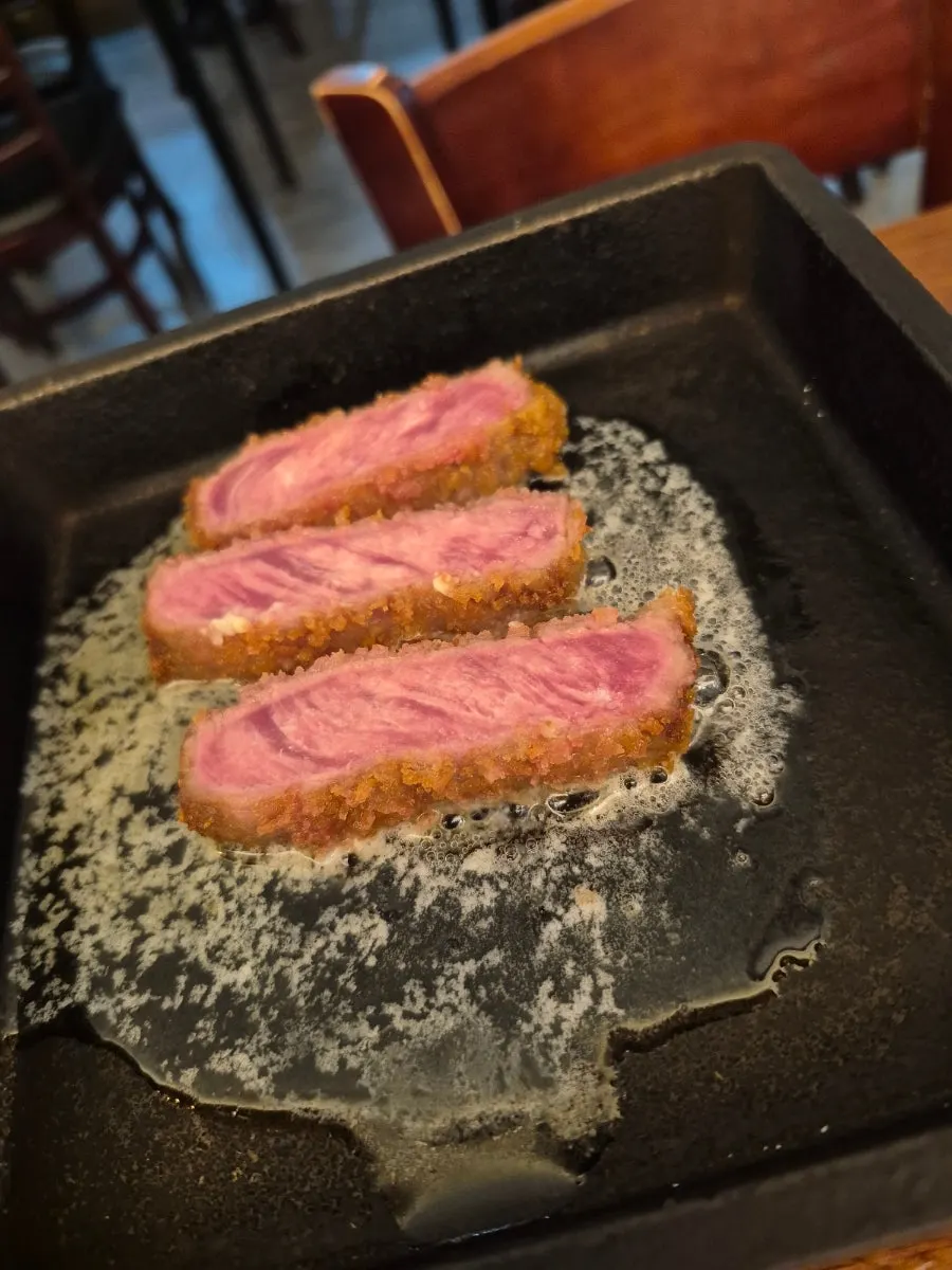 A slice of gyukatsu grilling in butter
