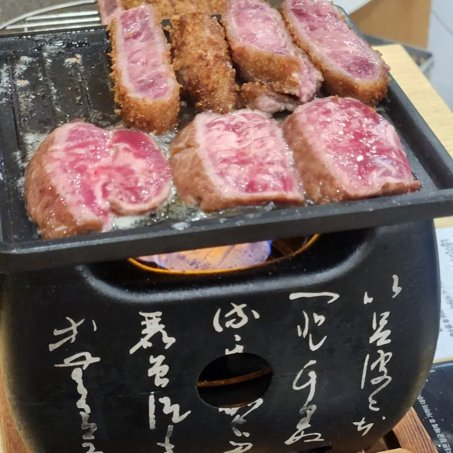 A piece of gyukatsu grilling on the brazier