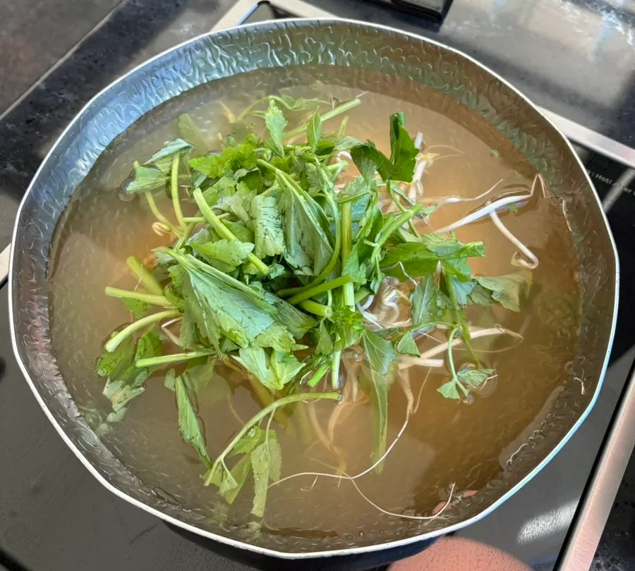 Shabu-shabu pot with clear anchovy broth and minari on top