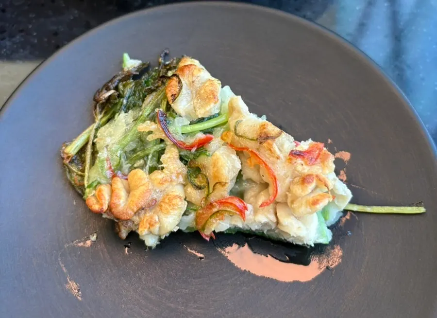 Plate of minari gonyi jeon topped with red and green chili peppers
