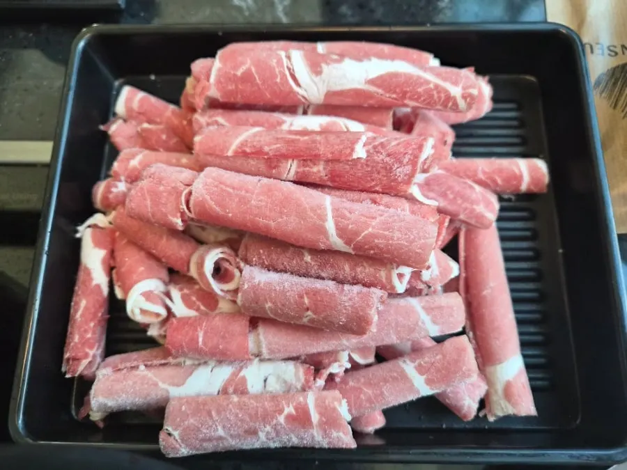 A plate of cooked meat and vegetables lifted out of the broth