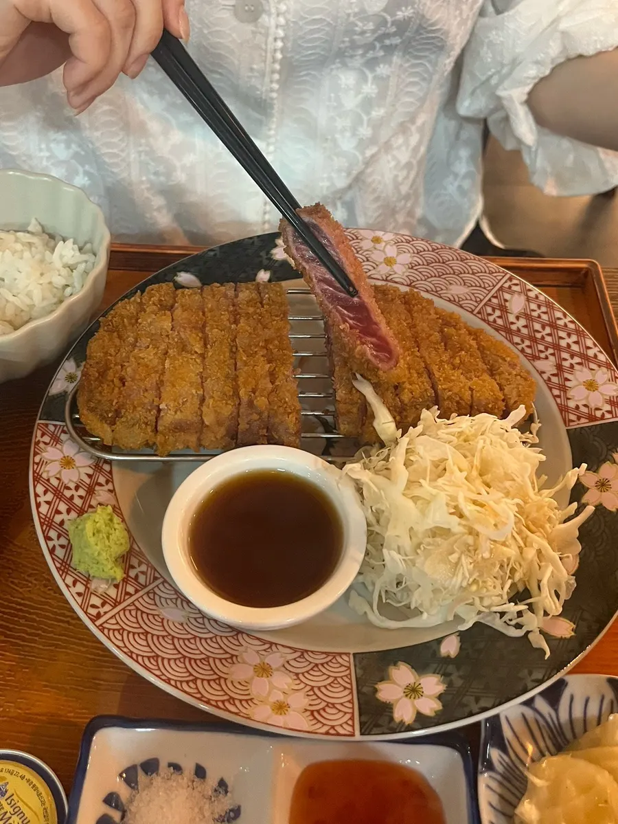 A piece of sirloin gyukatsu lifted with chopsticks