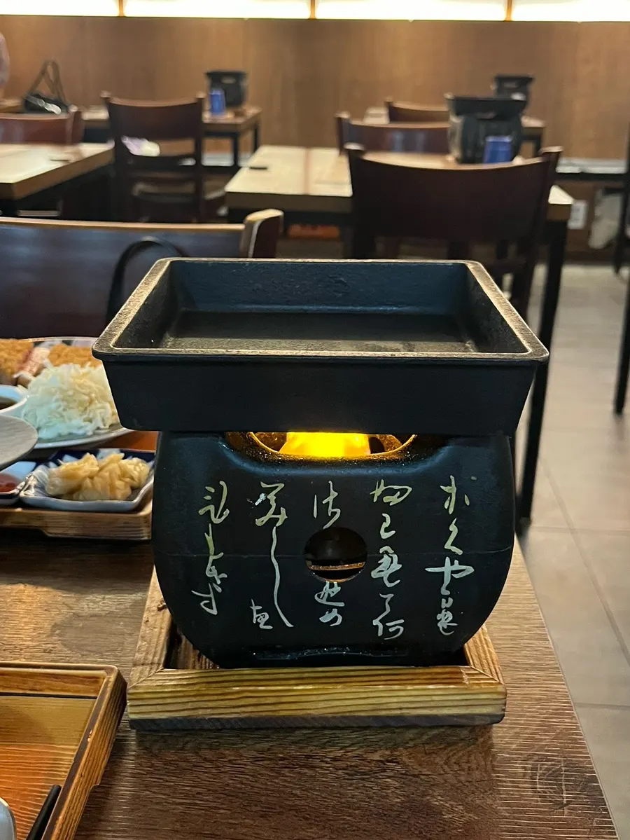 Grilling gyukatsu over a brazier topped with butter