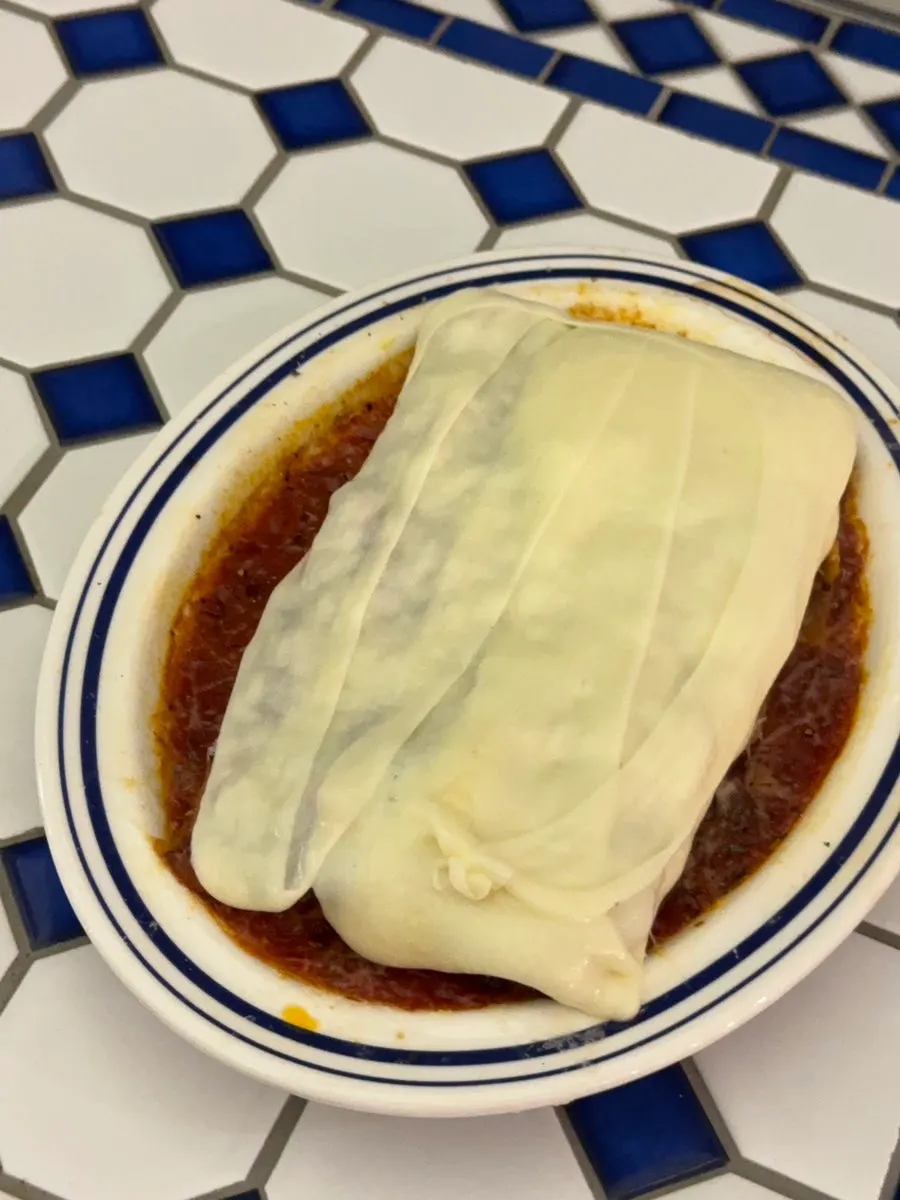 A single bite-sized portion of the lasagna with cheese pulled back