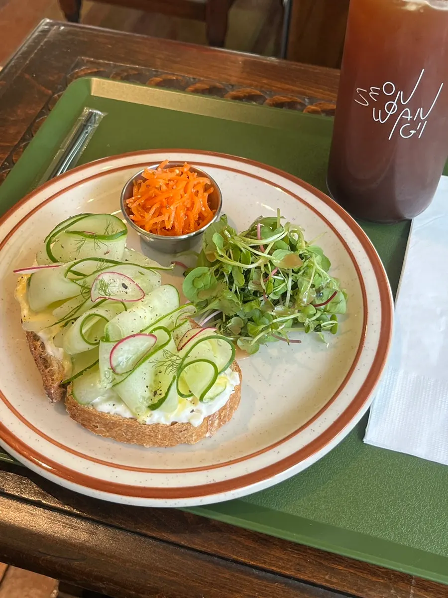 Table setting with iced Americano and cucumber egg ranch sandwich