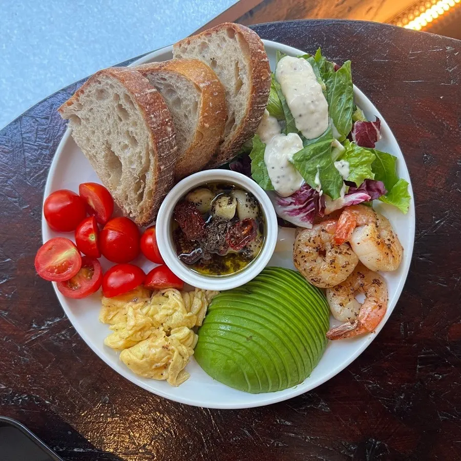 Grilled shrimp, avocado, scrambled eggs, and herb oil plate