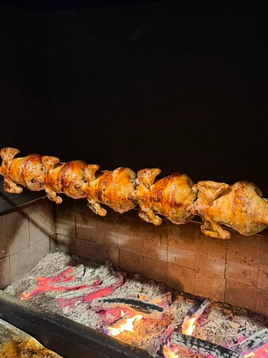 Whole chickens rotating over an oak charcoal fire