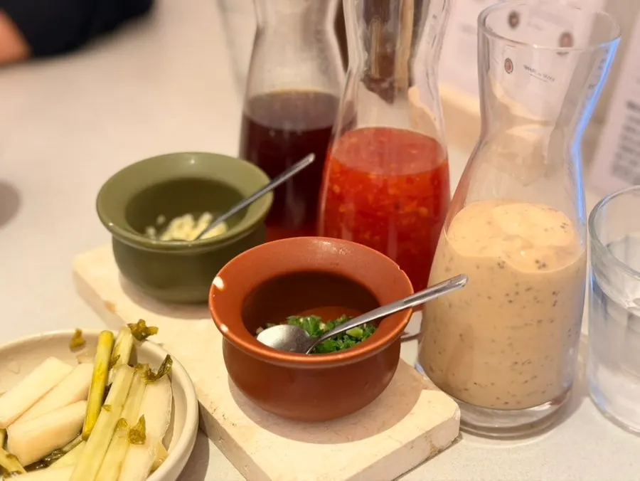 3 sauces served in bottles with chili peppers and garlic