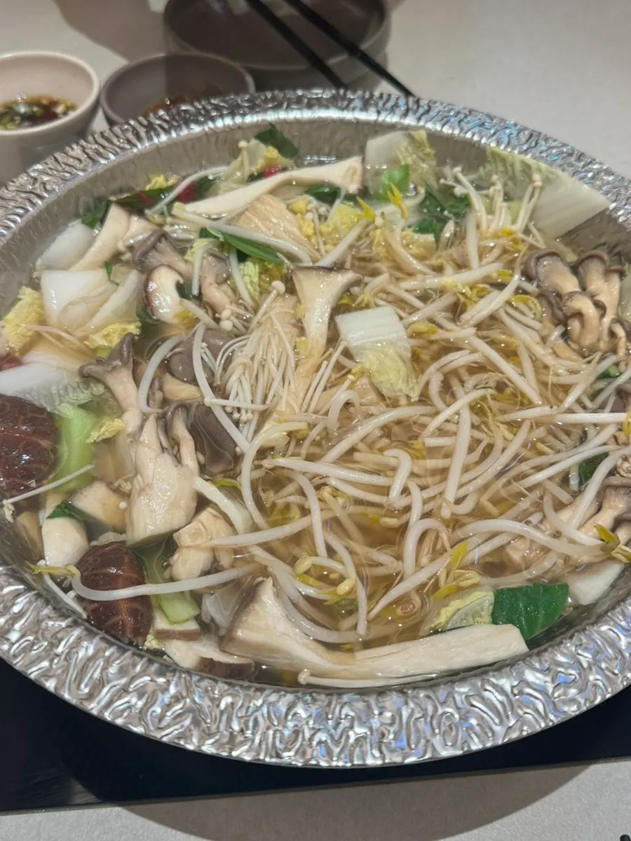Pot of clear mushroom broth simmering with vegetables