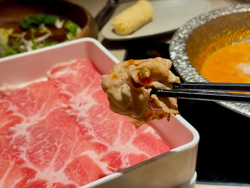 Black pork neck being briefly cooked in the broth