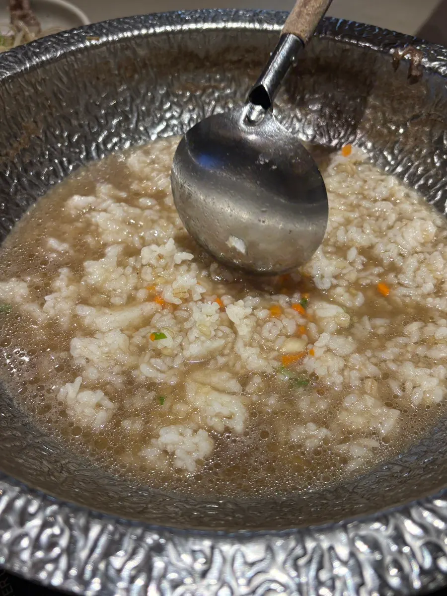 Pot of clear mushroom broth simmering with vegetables added